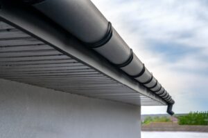 Close up of gutter system for a metal roof on a partly cloudy day.